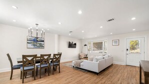 A modern living room with a white sofa, wooden dining table, and chairs. - Beautifully Modern Cottage in Historic Norcross (Norcross)