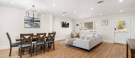 Una sala de estar moderna con un sofá blanco, una mesa de comedor de madera y sillas.