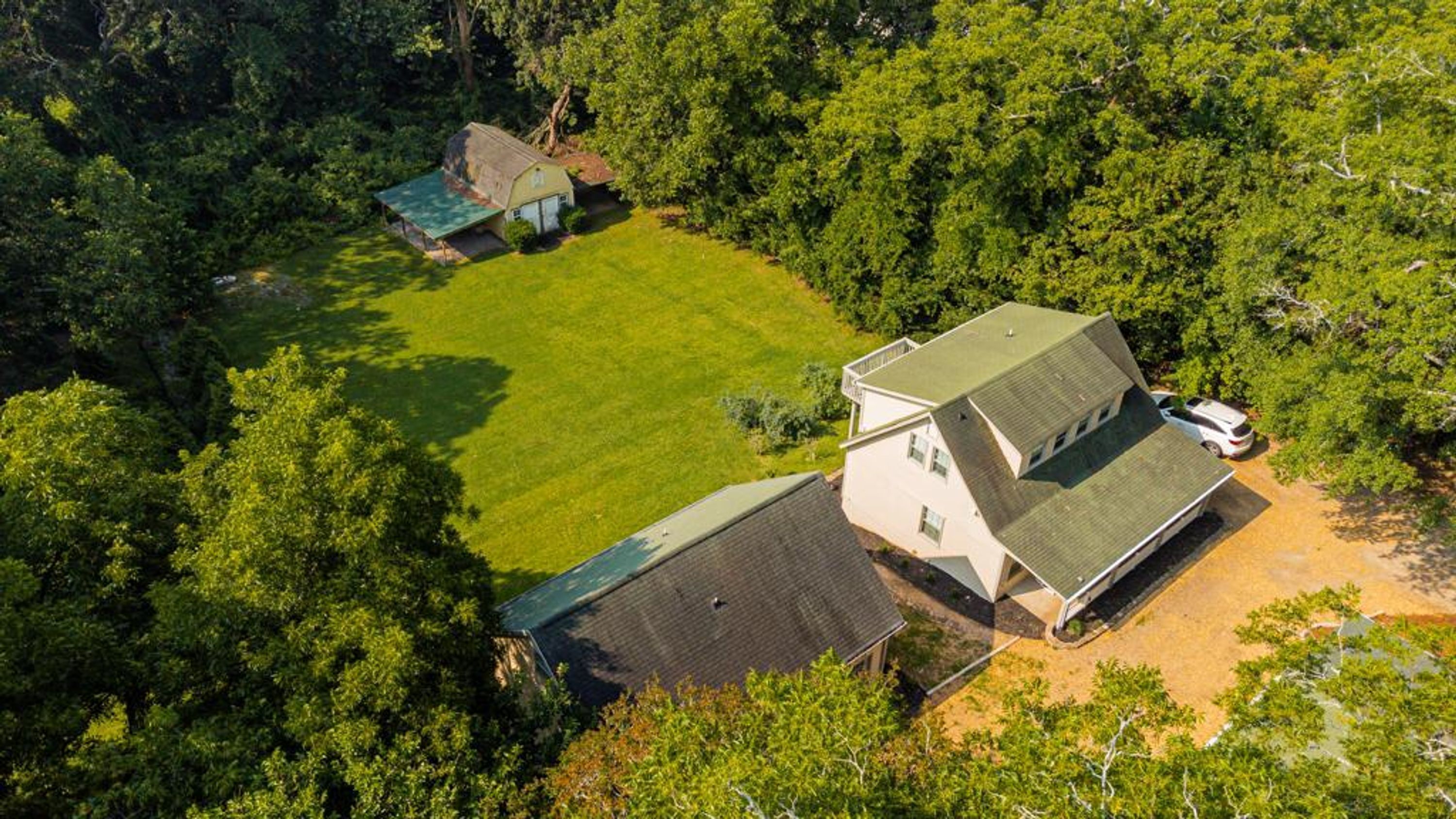 A large house with a spacious lawn, surrounded by dense trees.