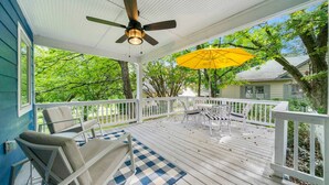 Eine überdachte Veranda mit Deckenventilator, Gartenmöbeln und einem gelben Sonnenschirm.