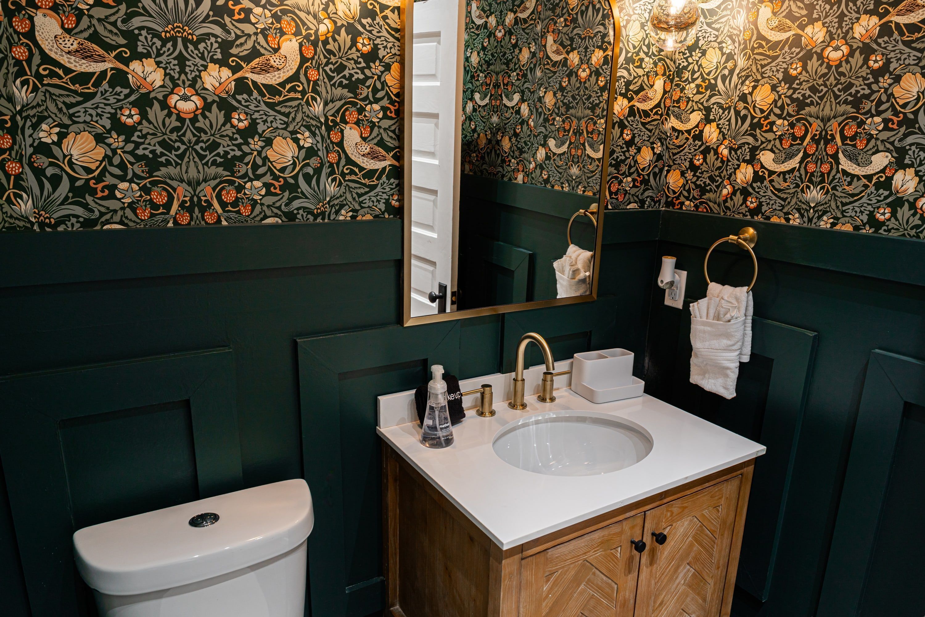 A bathroom with a toilet, a sink, and a mirror.