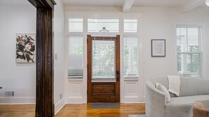 A spacious living room with hardwood flooring, a grey sofa, and a wooden door with blinds. - Beautiful Home Located In Historic Norcross (Norcross)