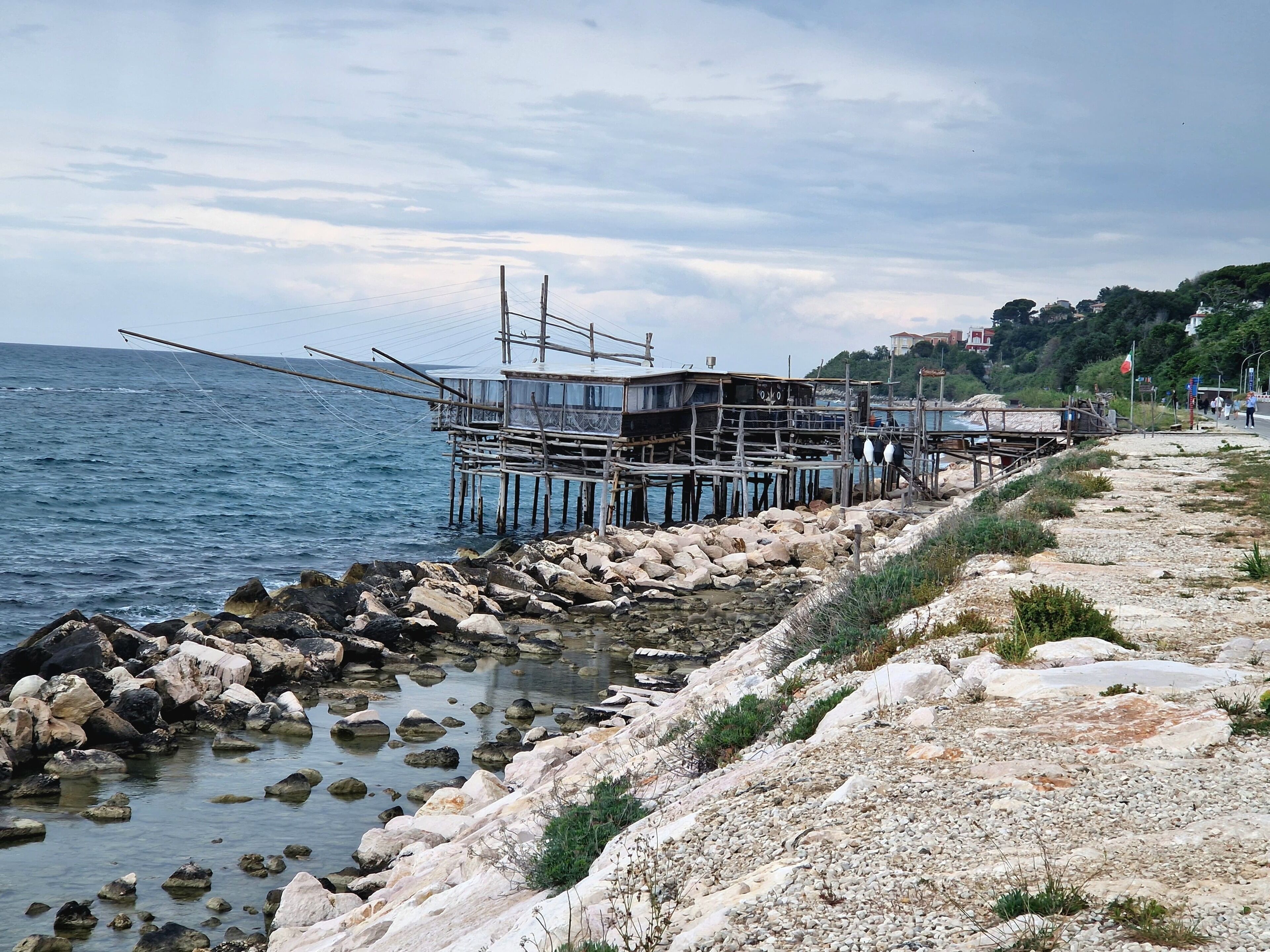 Eine Küstenlandschaft mit felsigem Ufer, einem Steg mit einem Gebäude und freiem Blick auf das Meer.