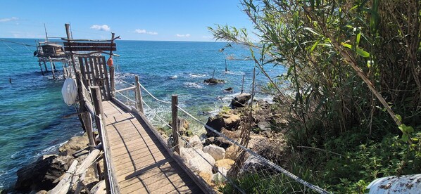 Un muelle de madera que se adentra en el mar, con un letrero que dice "TRABOC".