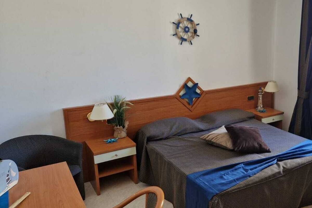 Un dormitorio con cama, mesitas de noche, escritorio y una silla.