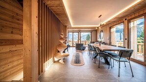 A modern wooden interior with a dining area, large windows, and a view of mountains.