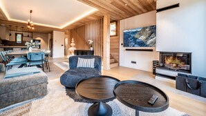 A modern living room with a fireplace, a dining area, and a kitchen.