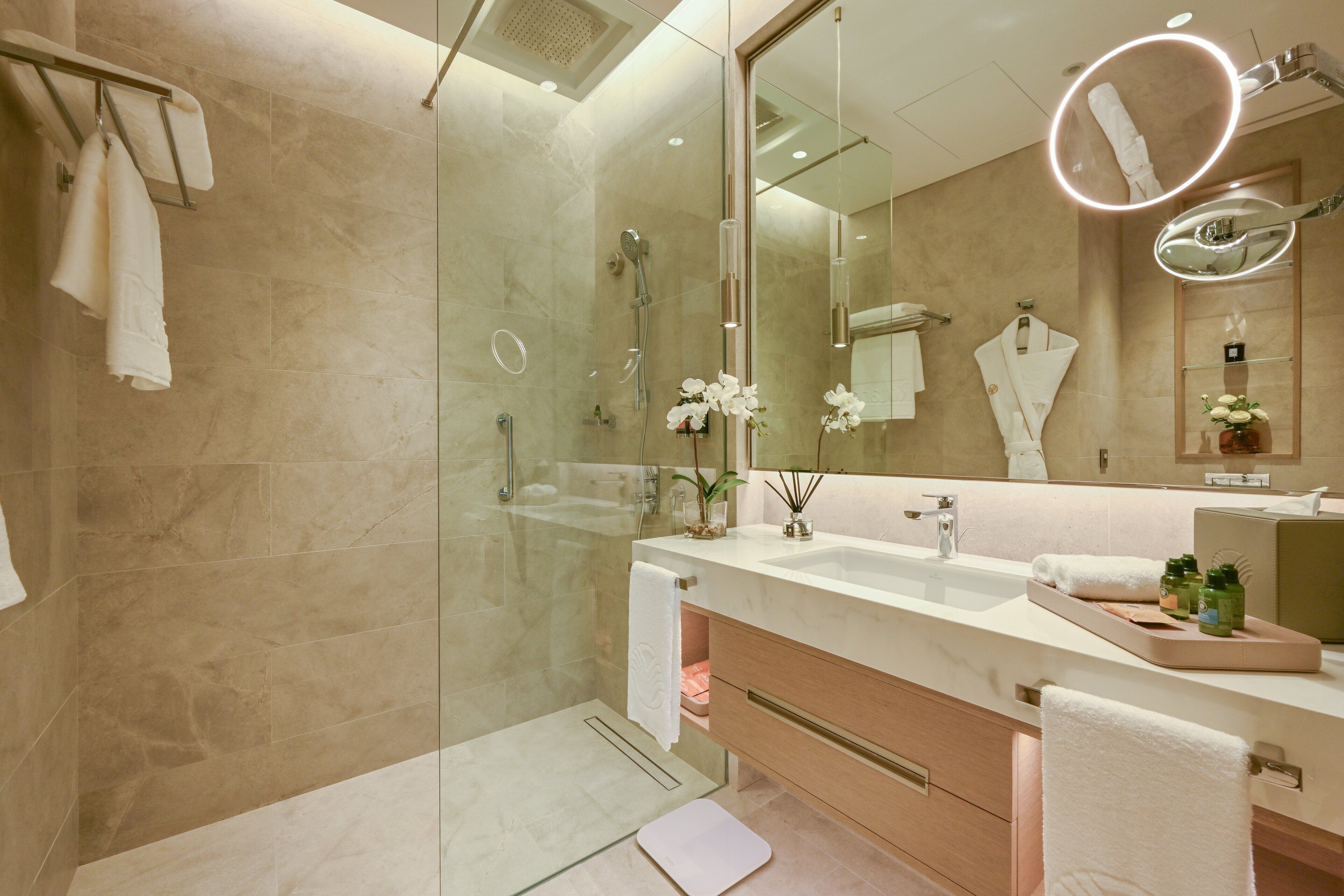 Un baño moderno con ducha de vidrio, un espejo grande y un tocador con encimera.