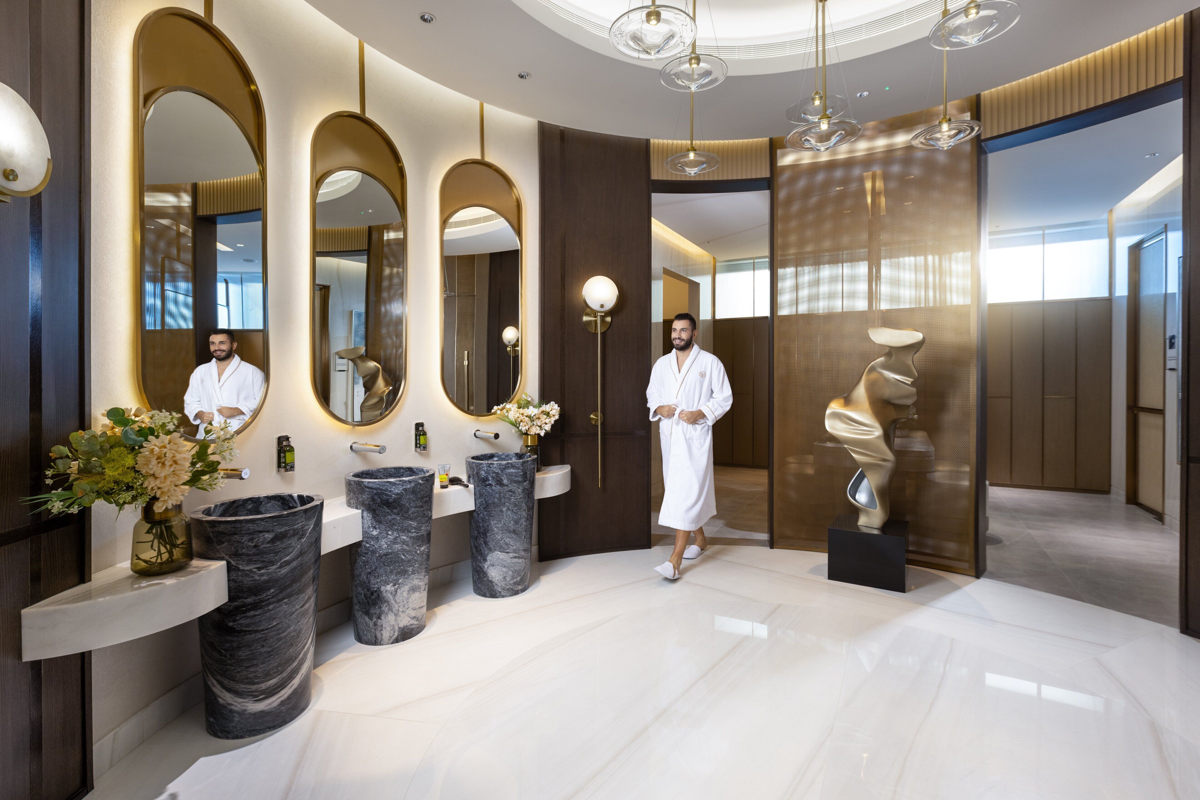 Une salle de bain moderne avec des vasques en marbre, de grands miroirs et un design minimaliste.