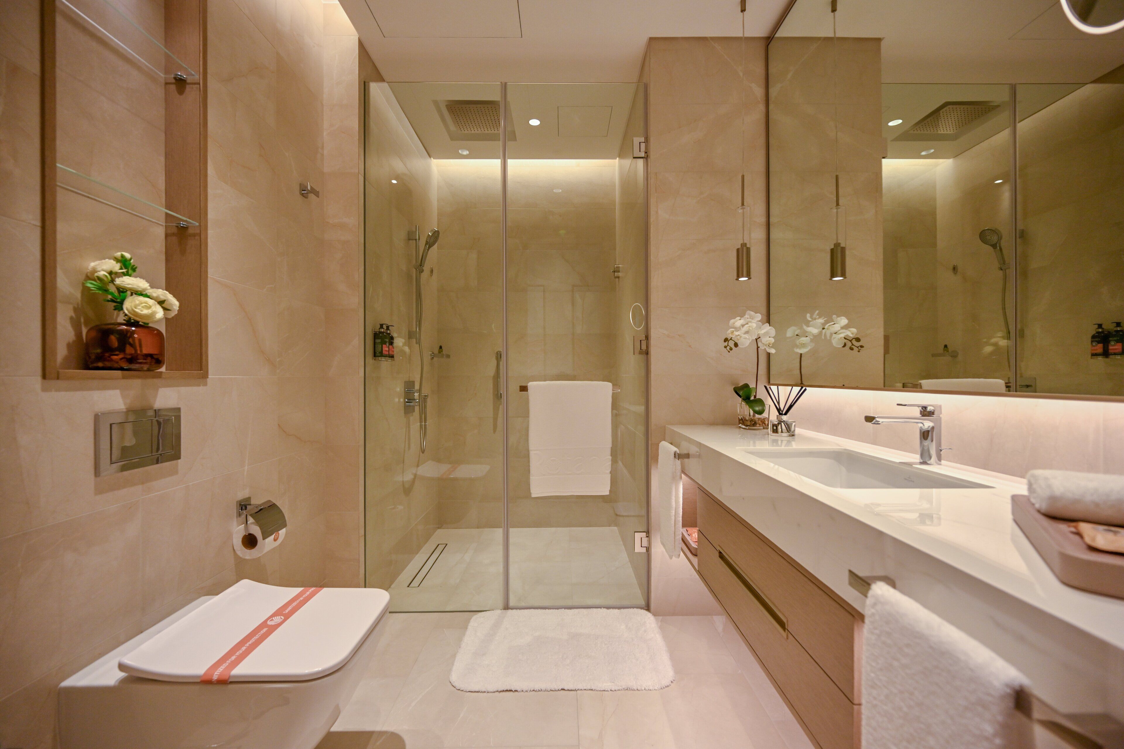 A modern bathroom with a glass-enclosed shower, a large mirror, and a dual sink vanity.