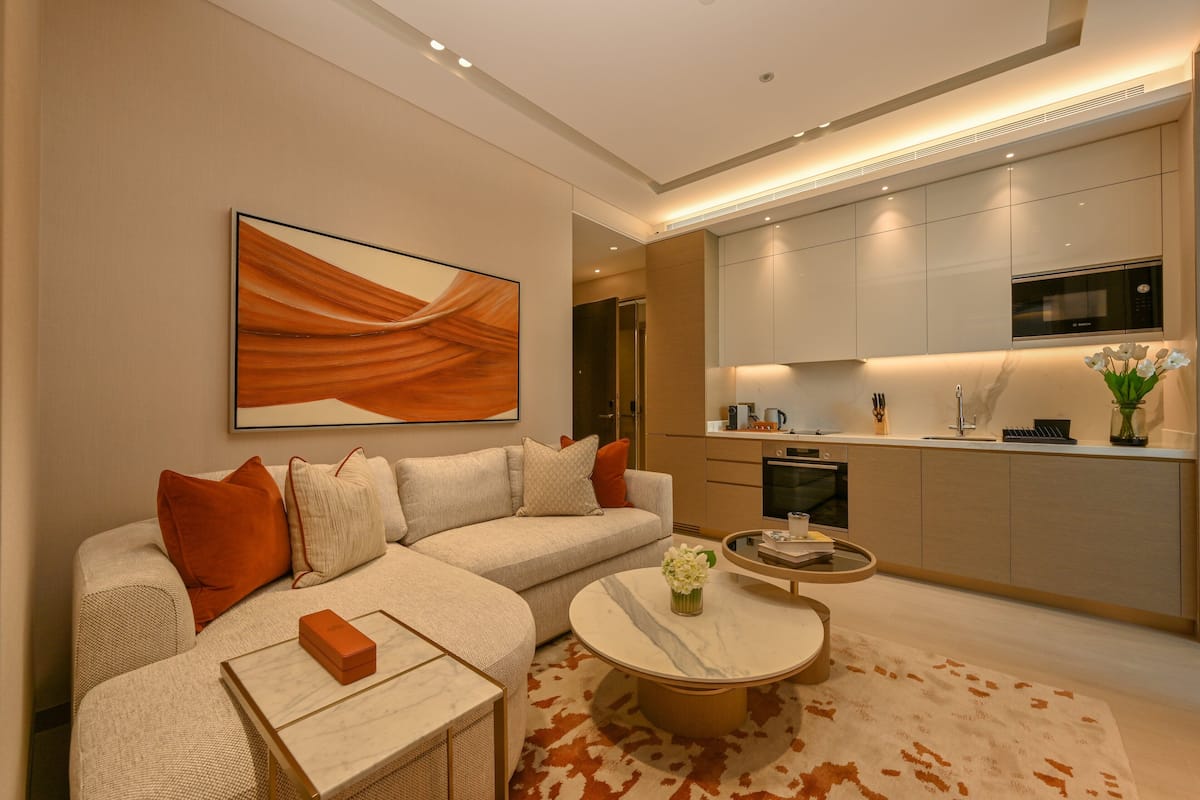 A modern living room with a sectional sofa, a coffee table, and a kitchen area with built-in appliances.