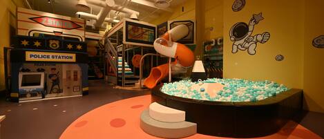 A children's play area with a police station theme, including a slide and a ball pit.