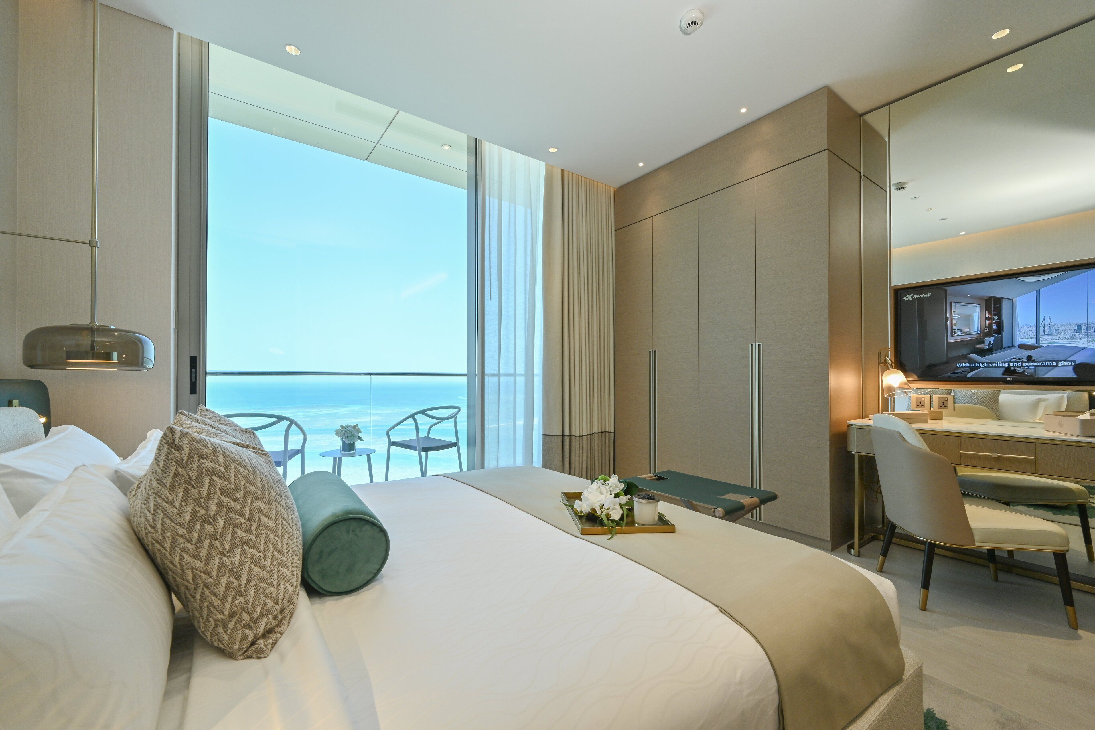 Una habitación de hotel moderna con una cama grande, un escritorio y vistas al océano.