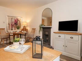 Una sala de estar con chimenea, televisor, mesa de comedor con sillas y un cuadro en la pared.
