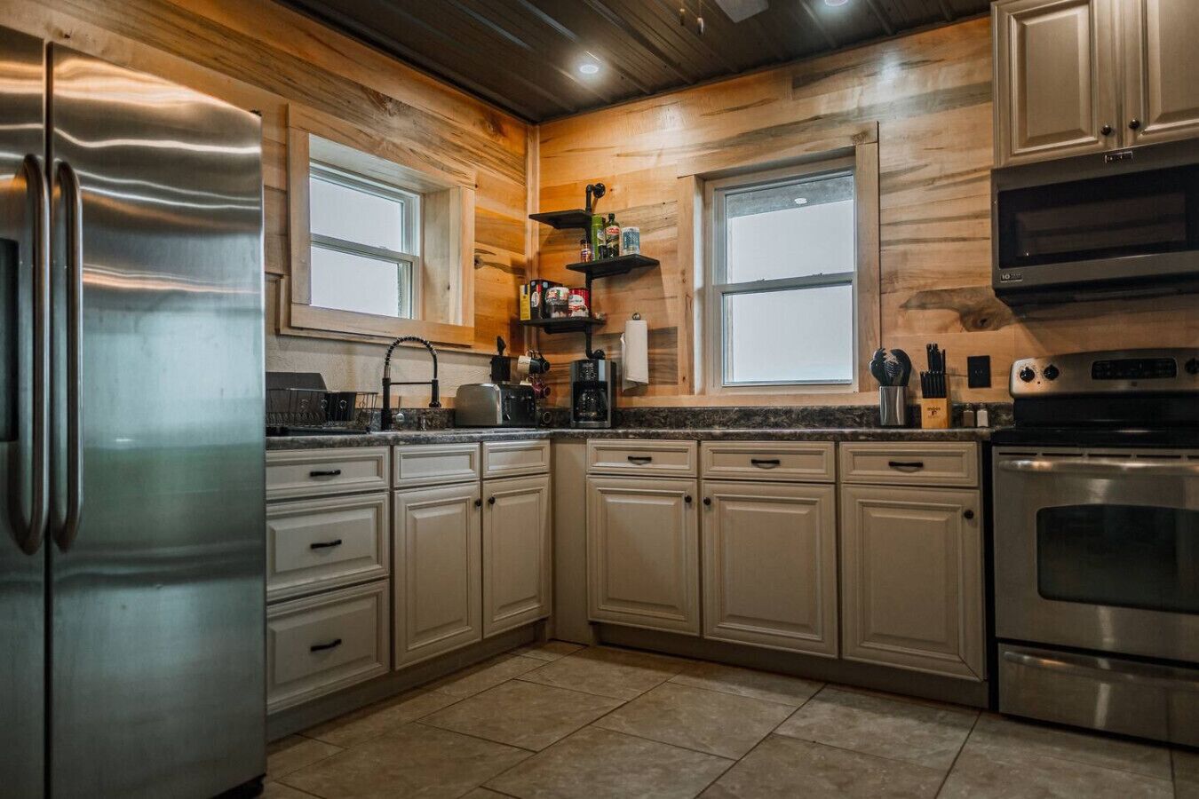 A modern kitchen with wooden cabinetry, stainless steel appliances, and a window above the sink.