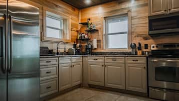 A modern kitchen with wooden cabinetry, stainless steel appliances, and a window above the sink.