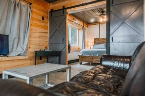A cozy room with a bed, a desk, a sofa, and a TV.