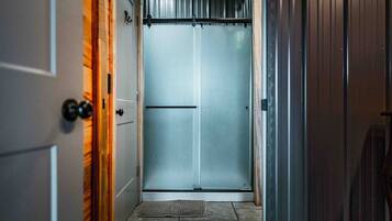 A narrow hallway with a door at the end leading to a room.