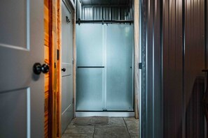 A narrow hallway with a door at the end leading to a room.