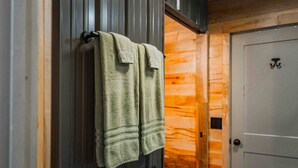 A bathroom with wooden walls, a towel rack with two towels, and a door with a symbol.
