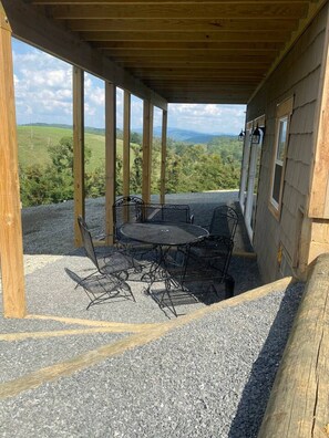 Un espace extérieur abrité, avec une table et des chaises, offrant une vue sur un paysage pittoresque.