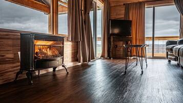 A cozy room with a fireplace, a television, and a view of the outdoors.