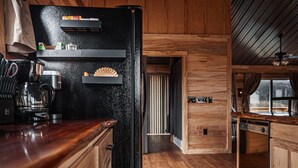 A kitchen with wooden cabinets, a black refrigerator, and a coffee maker.