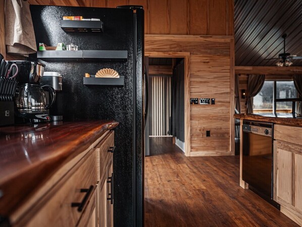 A kitchen with wooden cabinets, a black refrigerator, and a coffee maker.