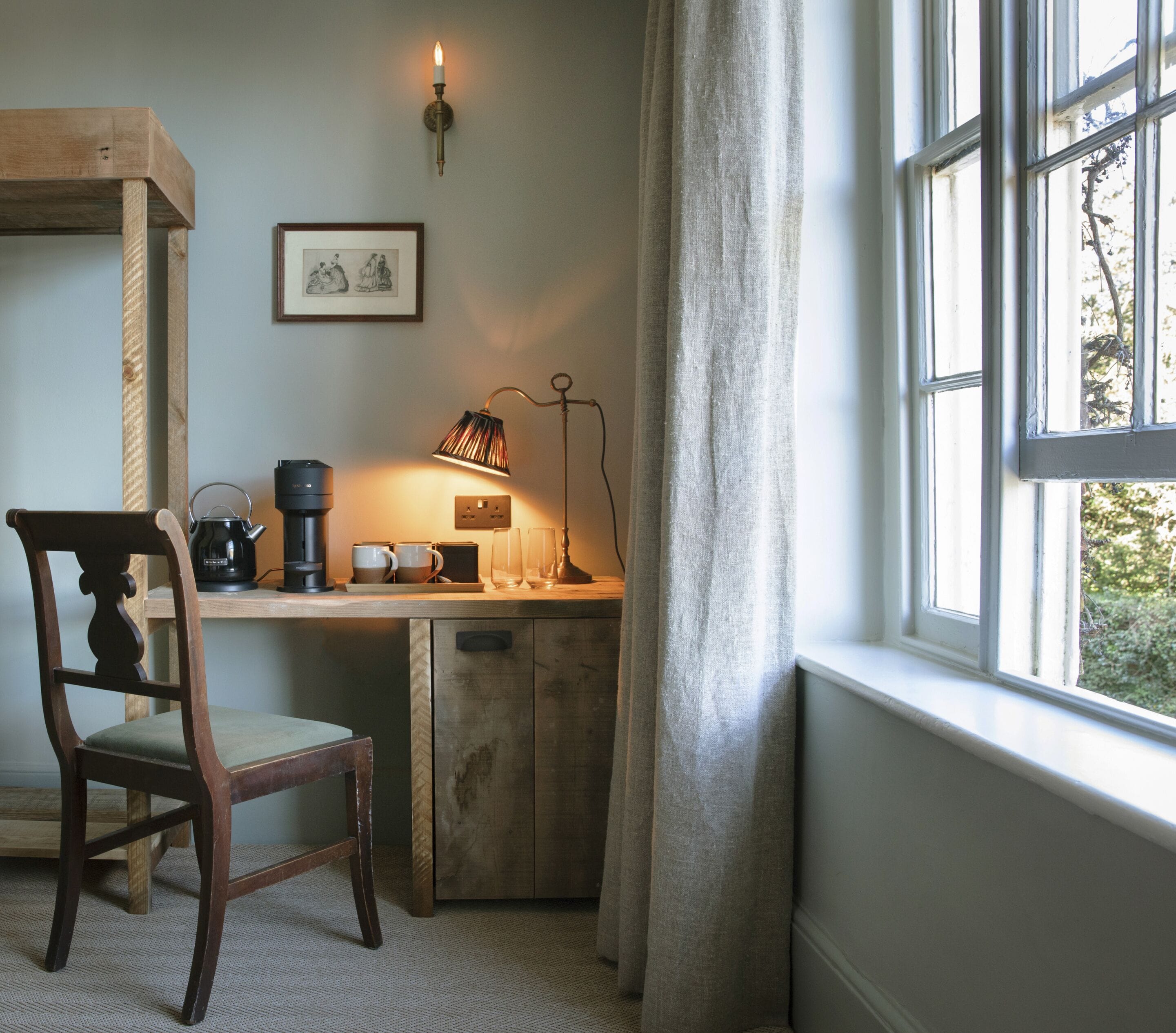 Un rincón acogedor con un escritorio de madera, una silla, una lámpara y una ventana con cortinas.