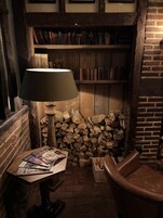 Un rincón acogedor para leer, con una estantería de madera, una lámpara y un sillón de cuero.