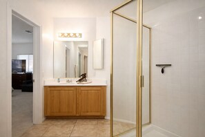 Un bagno con un mobile vanitario in legno, uno specchio grande e una cabina doccia in vetro.