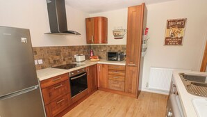 A kitchen with wooden cabinets, a stainless steel refrigerator, a microwave, and a stove. - Garden View (Pembroke)
