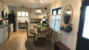 A modern kitchen with wooden cabinets, a dining table with chairs, a round rug, and a bench.