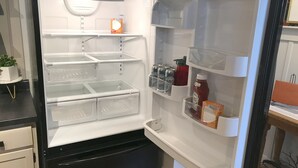 An open refrigerator with multiple shelves and compartments, including a section for beverages and a small section for condiments.