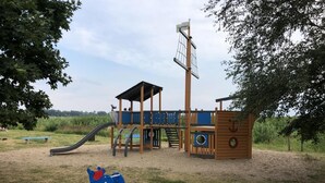 Une aire de jeux avec un toboggan, des structures d’escalade et un espace de jeu bleu en forme d’animal.