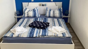 Une chambre à coucher avec un lit, des oreillers, une table de chevet, une lampe, un tapis et un tableau au mur.