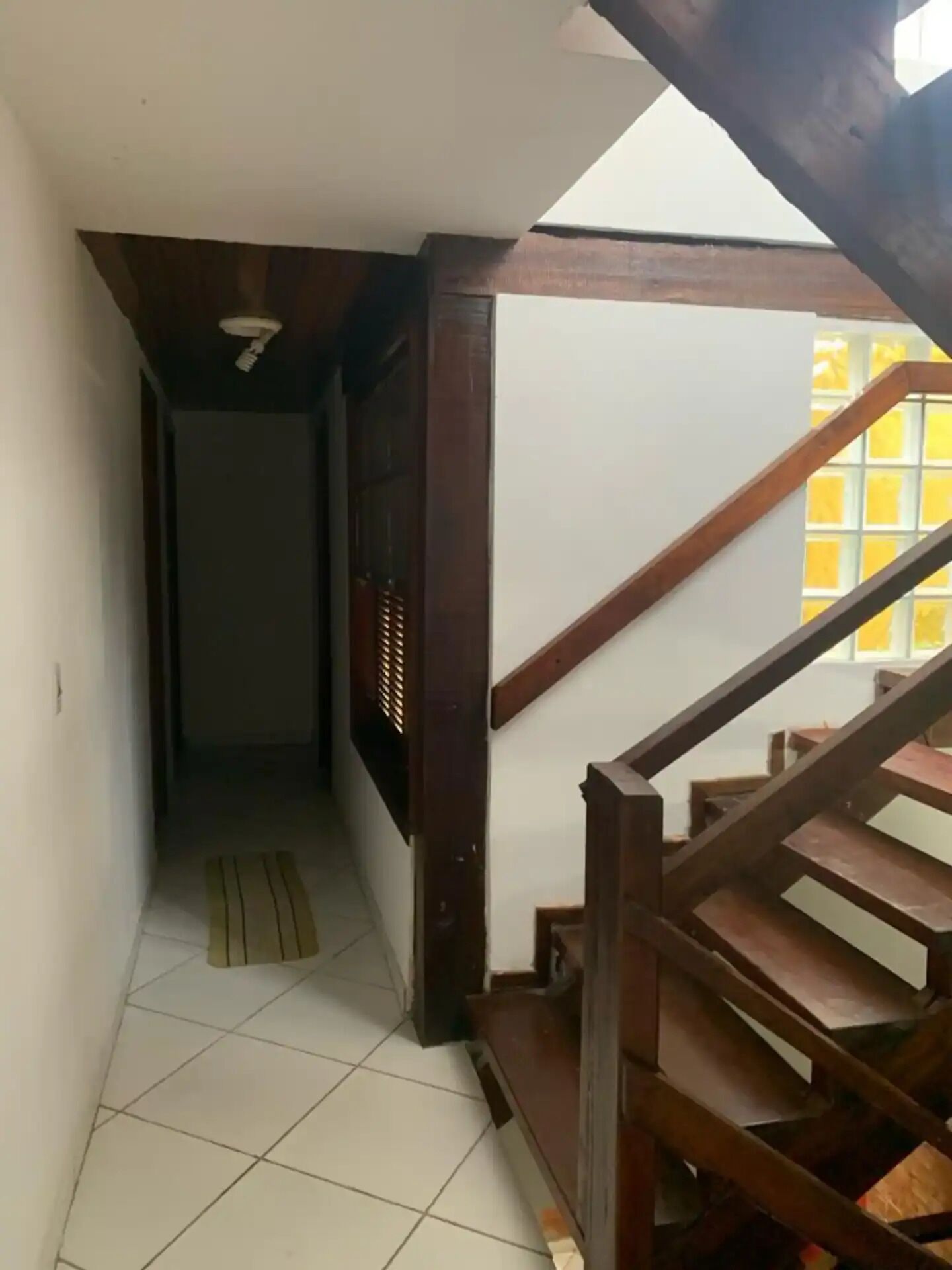 Una escalera con barandillas de madera y piso de baldosas.