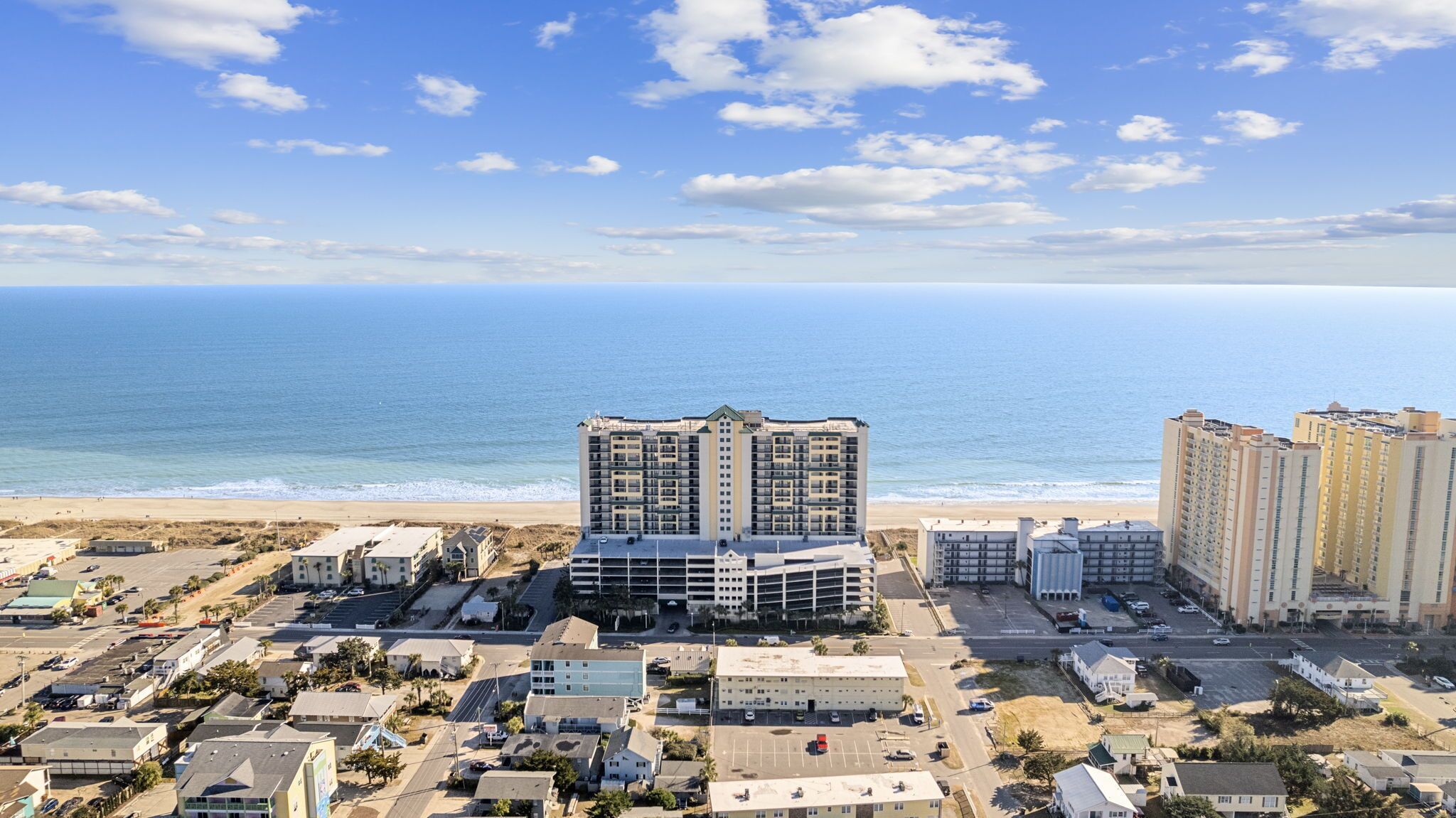 Eine Küstenlandschaft mit Hochhäusern, einem Strand und blauem Himmel.
