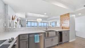 A modern kitchen with a large island, stainless steel appliances, and a view of the ocean. - Penthouse, 180° View, Lazy River, Hot Tub, Sleeps 12 (North Myrtle Beach)