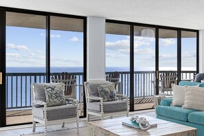 Un balcón con vistas al mar, amueblado con dos sillas y un sofá.