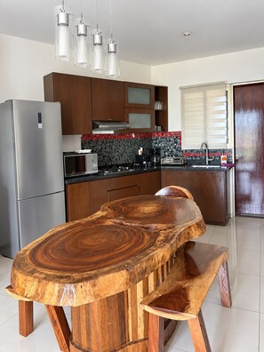 Una cocina moderna con una isla central, electrodomésticos de acero inoxidable y una mesa de madera original.