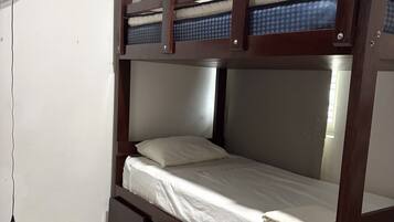 A bunk bed with a fan on the left, white bedding, and a tiled floor.