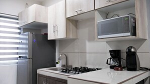 Eine Küche mit Kühlschrank, Mikrowelle, Herd und Kaffeemaschine.