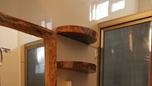 Ein Badezimmer mit einem Holzkosmetikschrank, einem großen Spiegel, einer Toilette und einer Duschkabine.