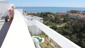Un balcon avec vue sur la mer, une piscine et les bâtiments environnants.