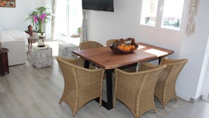 Un coin repas avec des chaises en osier, une table en bois et un panier de fruits.