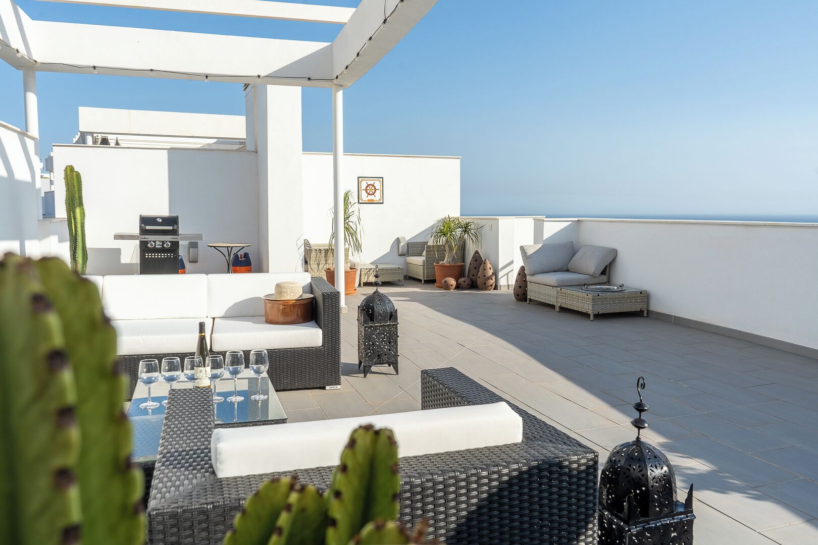 Une terrasse sur le toit avec des sièges extérieurs, une table avec des verres et une vue sur la mer.