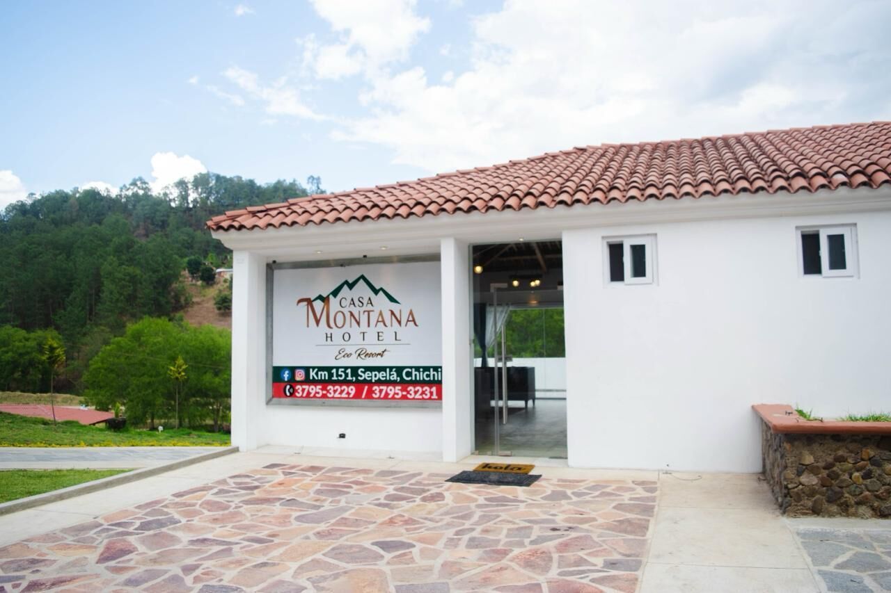 A Casa Montana Hotel with a tiled roof, stone-paved entrance, and a signboard with contact information.