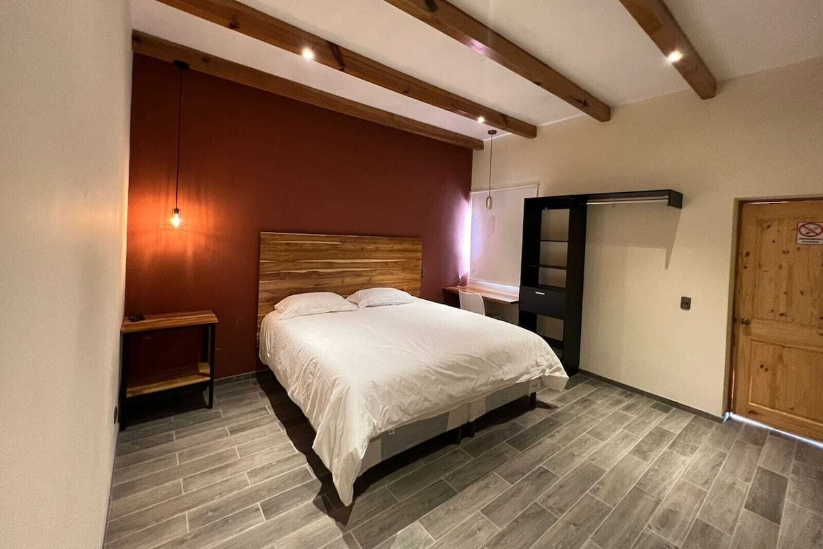 Un dormitorio con cama, escritorio y armario.