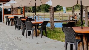 An outdoor dining area with tables and chairs, a pathway, and a building entrance.